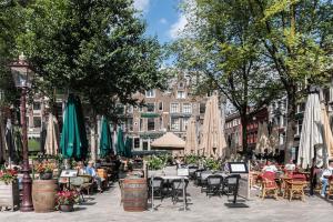 eine Stadtstraße mit Tischen, Stühlen und Sonnenschirmen in der Unterkunft CanalView Luxury Apartment in Amsterdam