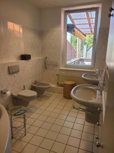 La salle de bains est pourvue de 2 lavabos, de toilettes et d'une fenêtre. dans l'établissement Gästehaus Harzstraße, 