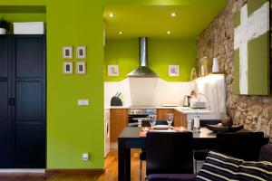 a kitchen with green walls and a table with chairs at Picasso Apartment in Barcelona