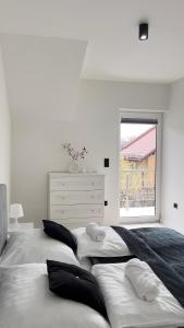 a white bedroom with two beds and a window at Apartament Lux SunRise in Żywiec