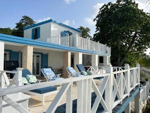 una casa con sillas azules y blancas en una terraza en North Star Villa Oceanfront Family-Retreat With Pool, en Frederiksted