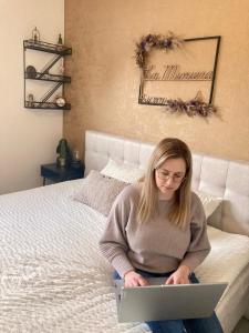 een vrouw op een bed met een laptop bij B&B La Miniera in Genk