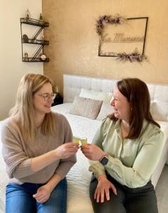 dos mujeres sentadas en una cama hablando y riendo en B&B La Miniera, en Genk