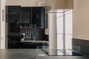 uma cozinha com armários pretos e uma mesa de vidro em Casa Penelope em Milão
