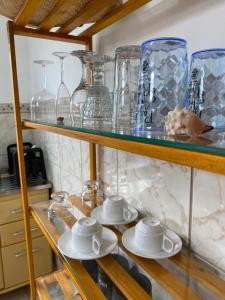 a glass shelf with glass vases and saucers on it at Casa Quintal - Pé na Areia - Araçatiba Ilha Grande in Praia de Araçatiba