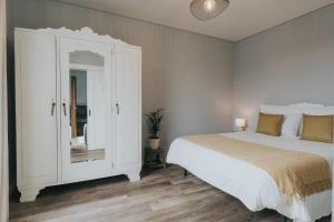 a white bedroom with a bed and a cabinet at Pico Apartment's in Câmara de Lobos