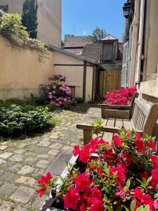 a patio with two benches and red flowers at Appartement Versailles château in Versailles