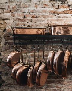 シナルンガにあるPodere Pievina Delle Corti - Dimora di Campagnaの煉瓦の壁に吊るされた銅鍋