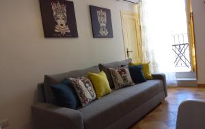um sofá cinzento com almofadas coloridas numa sala de estar em L'Appartement dans les Venelles em Cefalù