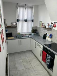a kitchen with white cabinets and a sink and a stove at 2-Bedroom Flat w/ En-Suites, Perfect for Groups in Liverpool