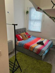 a small bedroom with a bed with a blanket at 2-Bedroom Flat w/ En-Suites, Perfect for Groups in Liverpool