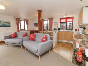 a living room with two couches and a kitchen at Tarquol Cottage in Little Torrington