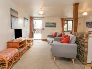 a living room with two couches and a tv at Tarquol Cottage in Little Torrington