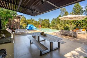 a patio with a table and an umbrella and a pool at Modern village between mountains Villa la Justina in Constanza