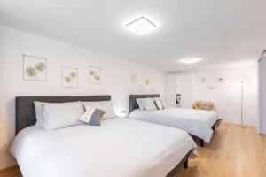 twee bedden in een kamer met witte muren en houten vloeren bij Loft Salgari in Turijn