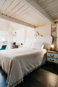 a bedroom with a large white bed and a kitchen at Le Contrade Chiasso Cafaro in Monopoli