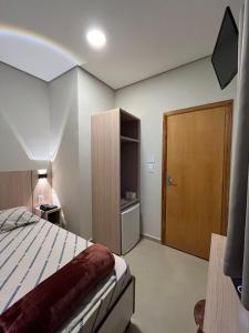um quarto com uma cama e uma porta de madeira em Hotel Neon - próximo a 25 de março, Bom Retiro e Brás, á 2min do mirante Sampa SKY e pista de skate Anhangabaú em São Paulo