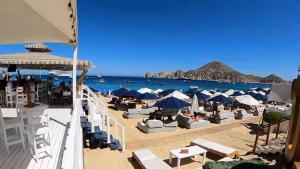 a beach with chairs and umbrellas and the ocean at Marina Sol in Cabo San Lucas