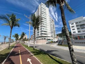 une rue vide avec des palmiers et un grand bâtiment dans l'établissement Pé na areia, Solemar Praia grande, à Praia Grande
