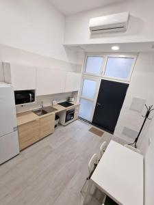 a white kitchen with a table and a white refrigerator at Loft Seco super equipado cerca de metro Pacífico in Madrid