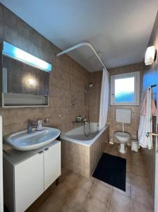 a bathroom with a sink and a tub and a toilet at Gemütliche 3-Zimmer-Wohnung im schönen Murten. in Murten