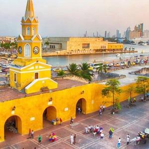 um edifício amarelo com uma torre de relógio numa cidade em casa frente al mar Cartagena em Cartagena das Índias