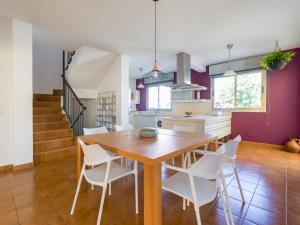 uma cozinha e sala de jantar com uma mesa de madeira e cadeiras brancas em Villa Los Olivos em San Bartolomé