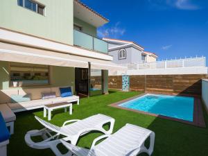 a backyard with a swimming pool and chairs and a house at Villa Los Olivos in San Bartolomé de Tirajana