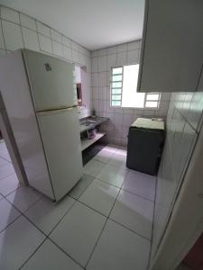 a white kitchen with a refrigerator and a window at Casa Indaia Caraguatatuba in Caraguatatuba