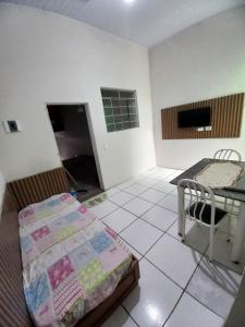 a room with a bed and a table in it at Casa Indaia Caraguatatuba in Caraguatatuba