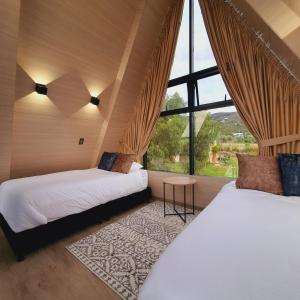 2 camas en una habitación con ventana grande en Cádiz Hotel Boutique en Villa de Leyva