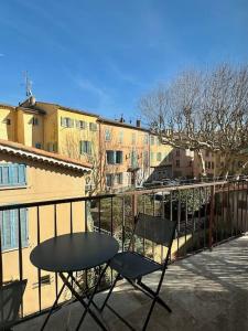 een tafel en 2 stoelen op een balkon met gebouwen bij Appartement lumineux avec terrasses in Le Luc