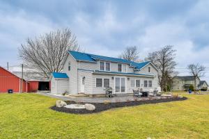 a white house with a blue roof on a yard at Auburn Finger Lakes Farmhouse with Open Views! in Auburn