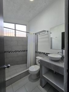 a white bathroom with a toilet and a sink at Tropical Paradise in Jacó
