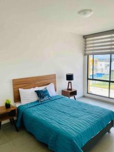 um quarto com uma cama com um edredão azul e uma janela em Amplia casa cerca de zona industrial em San Luis Potosí