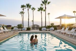 duas mulheres sentadas na piscina de beiral infinito do resort em Beach Village at The Del, Curio Collection by Hilton em San Diego