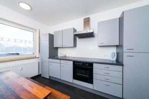 une cuisine avec des placards blancs, une table et une fenêtre dans l'établissement Gabriel´s Apartment´s, à Dortmund