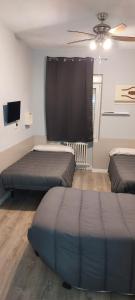 アランダ・デ・ドゥエロにあるHostal Rosalesのベッド2台、薄型テレビが備わる客室です。