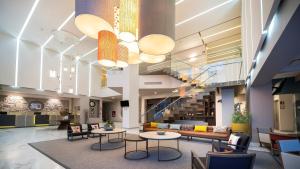 a lobby with tables and a couch and stairs at Metria Hotel in León