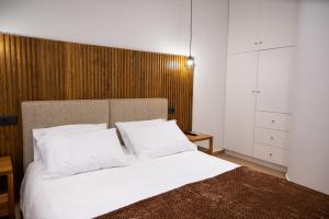 1 dormitorio con cama blanca y cabecero de madera en Kefaloviso Luxury Apartment 2, en Nafpaktos