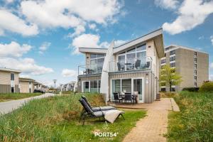 a house with chairs and a table in front of it at Ferienhaus Kleine Düne Marina Wendtorf in Wendtorf