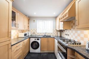 - une cuisine avec des placards en bois et un lave-linge/sèche-linge dans l'établissement Space Apartments - 3 Bed House Broomfield Chelmsford, à Chelmsford