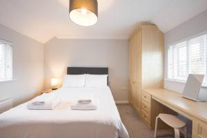 - une chambre avec un lit blanc, un bureau et des fenêtres dans l'établissement Space Apartments - 3 Bed House Broomfield Chelmsford, à Chelmsford