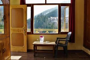 um quarto com uma mesa, uma cadeira e uma janela em Divine blessing em Manali