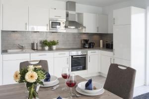 a kitchen with white cabinets and a table with glasses of wine at Bootshaus in Olpenitz