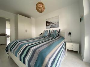 um quarto com uma cama com um cobertor listrado azul e branco em Bootshaus em Olpenitz