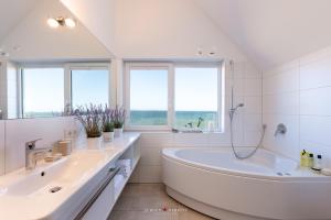 a white bathroom with two sinks and a tub at An der Ostsee 17 in Olpenitz