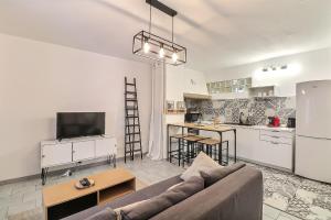 een woonkamer met een bank en een keuken bij Hyper Centre Terrasse Wifi La Pierre d'Histoire in Beaucaire