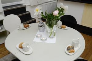 uma mesa branca com um vaso de flores e bolachas em Albatros em Flensburg