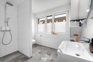 a white bathroom with a shower and a sink at Küste 3 in Büsum